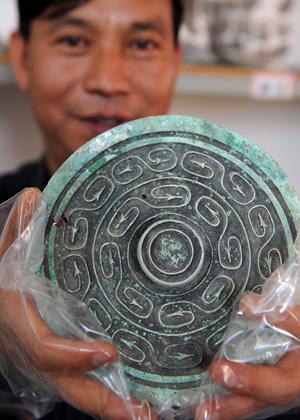 Ein Arch?ologe zeigt eine alte Bronze-Dekoration, die in den Jinlian-Bergen im Kreis Dengjiang in der südwestchinesischen Provinz Yunnan entdeckt worden ist.