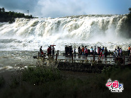 Viele Touristen stehen auf einer Terrasse und beobachten den Wasserfall.