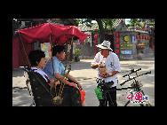 Ein Rikscha-Fahrer erzählt den Touristen über die Geschichte Beijings. 