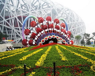Touristen machen Fotos vor einer riesigen Dekoration beim Nationalstadion, dem Vogelnest, in der chinesischen Hauptstadt Beijing. Der Olympiapark, in dem sich das Vogelnest befindet, wurde zur Feier des 60. Jahrestags der Gründung der Volksrepublik China für den 1. Oktober in Schale geworfen.