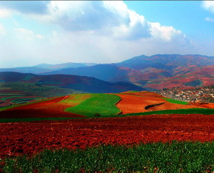 In Yunnan gibt es ein Märchenland, das für seine rote Erde bekannt ist. Geschmückt mit bunten Pflanzen, die ihre Farben im Verlaufe der Jahreszeiten ändern, erschaft die Gegend eine Szenerie, die an einen Regenbogen erinnert.