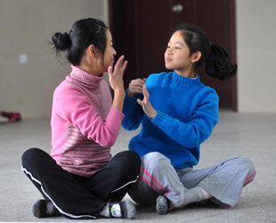 Die taubstummen Schülerinnen Liu Yidan (rechts) und Luo Yanan (links) verständigen sich während des Tanzunterrichts durch Zeichensprache in einer Förderschule der Stadt Yichang in der zentralchinesischen Provinz Hubei; 19. November 2009.
