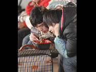 Ein junges Paar teilt eine Schüssel Instant-Nudelsuppe auf dem Westbahnhof Beijings, während es auf den Zug wartete.