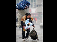 Im Bahnhof von Nanchang, der Hauptstadt der zentralchinesischen Provinz Jiangxi, trägt eine Wanderarbeiterin ein riesiges Bündel und ihr Baby.  