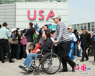 Ein Besucher fährt mit dem Rollstuhl am Pavillon der USA vorbei.
