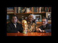 Der ehemalige südafrikanische Präsident Nelson Mandela lässt sich in der Nelson-Mandela-Stiftung in Johannesburg mit dem Vorsitzenden des Organisationskomitees, Danny Jordaan (l.) und dem FIFA-Generalsekretär Jerome Valcke (r.) zusammen mit dem WM-Pokal fotografieren (6. Mai 2010). [China Daily/Agenturen]