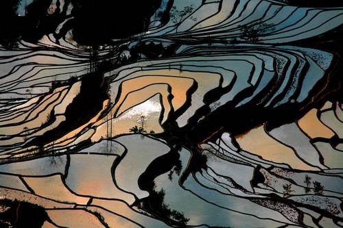 Man sagt, Yuanyang sei der beste Ort in Yunnan, um einen Sonnenuntergang zu fotografieren. Das Abendrot ist hier nicht nur im Himmel, sondern überall zu spüren. Der Wind singt dazu sein Lied und zieht über die bunten Terrassenfelder.