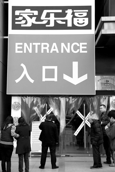 昨日，市民在家乐福郑州花园路店门口观看停业通告。图/CFP