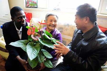 In einem Wohnviertel in der Stadt Qingdao der chinesischen Provinz Shandong schenkte ein Freiwilliger aus Guinea einer alten chinesischen Dame eine Blume zum chinesischen Fest Xiaonian.