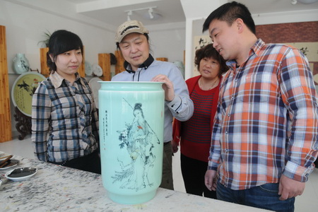 Am 10. April bewunderte ein Meister der Keramik-Kunst namens Wang Yijun das Gemälde 'Heimkehr mit Grüne im Frühling' auf einer Porzellanvase aus Seladon in der Provinz Shandong.