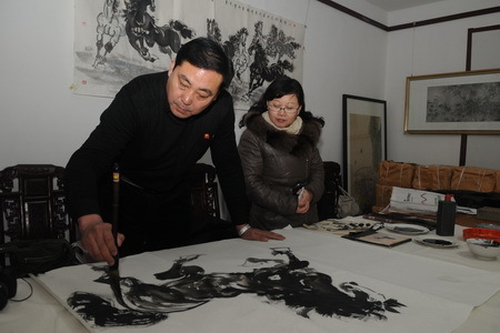 Das Foto zeigt, wie Liu Xufeng (links), Mitglied des Malervereins der Provinz Shandong, am 15. Januar in der Wenfeng-Akademie für Kalligrafie und Malerei, die im Bezirk Zichuan der Stadt Zibo liegt, mit Tusche ein Pferd malt.