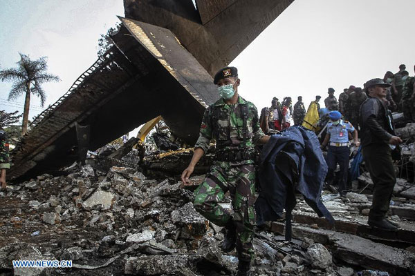 Security members work at the crash site of an Indonesian military plane Hercules C-130 in the capital of North Sumatra province Medan, Indonesia, on June 30, 2015.