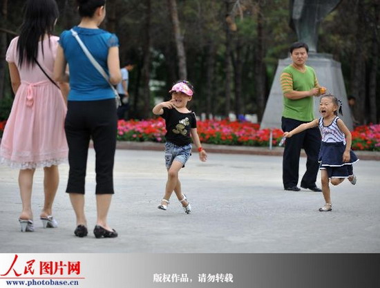 7月10日下午，乌鲁木齐市民带着孩子正在人民公园游玩。记者翁奇羽摄