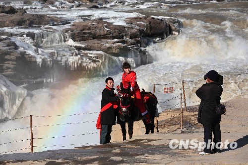  12月20日，一对新人在冰冻成型的黄河壶口瀑布前留影。