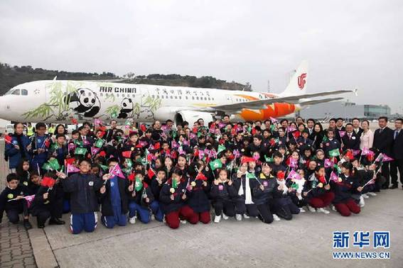 12月18日，迎接“开开”“心心”的澳门小学生与各界嘉宾在澳门国际机场大熊猫专机前合影
