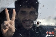 リビアの東部で、トラックの中でVサインをする反政府武装兵。ガラスが銃弾を受けた