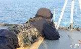 海上に浮かぶターゲットに照準を合わせて、射撃する兵士。  