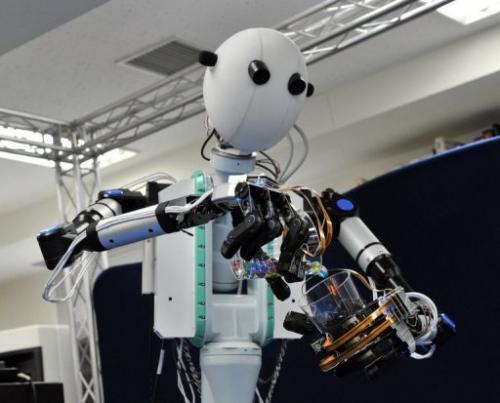 这是在日本庆应大学实验室的一场演示中，机器人在远程操控下将玻璃弹子从一个杯子中倒入另一个杯子