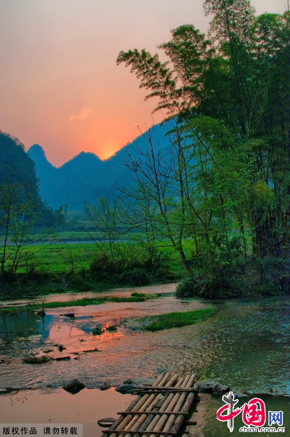 夕阳落日时分的坝美村，落日映照着群山，云层中不再耀眼的光线洒在山峦上，让人如痴如醉。中国网图片库 张旭摄影