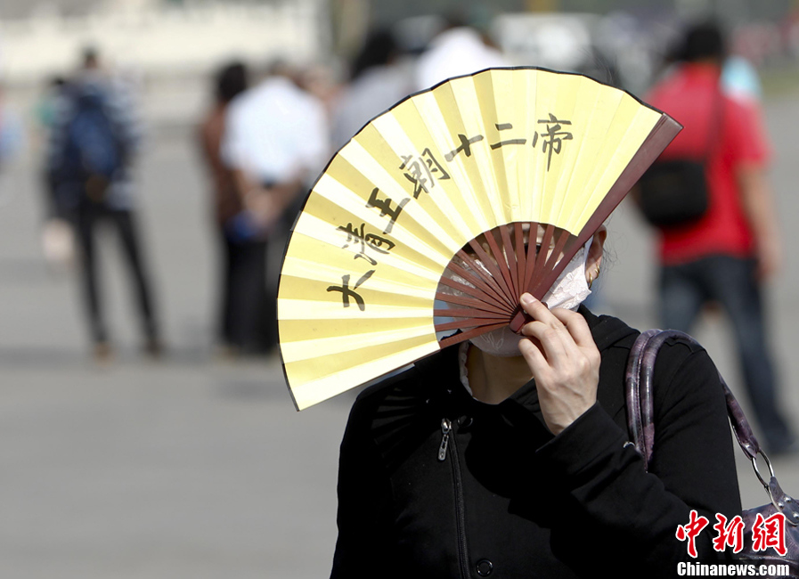 北京持续高温 游客以扇遮阳