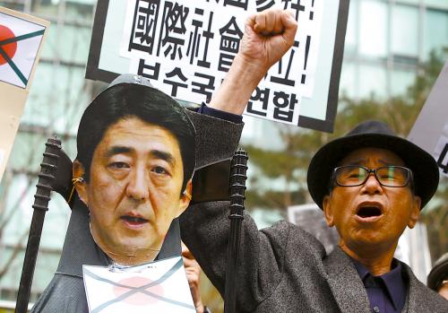 韓国の民衆が25日、在韓国日本大使館前に集まって安倍首相の顔写真をつけた人形を燃やし、安倍首相の参拝を支持する発言に抗議した。