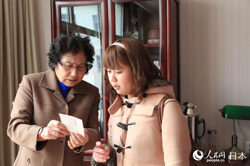 游学团成员参观老人房间，老人给成员展示女儿从日本寄来的明信片。