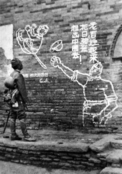 这张图是1938年3月初日军进犯临汾时所拍，地点在临汾的抗日学生游击队学校，一名日军正在观看学校大门上的宣传文字。