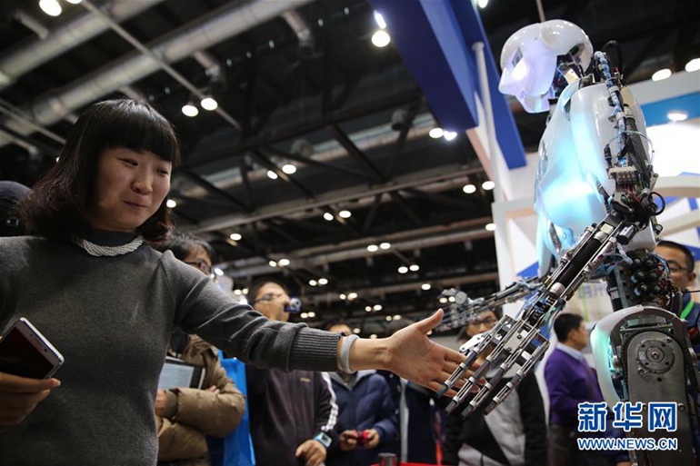 11月24日，一位参观者在同机器人握手。