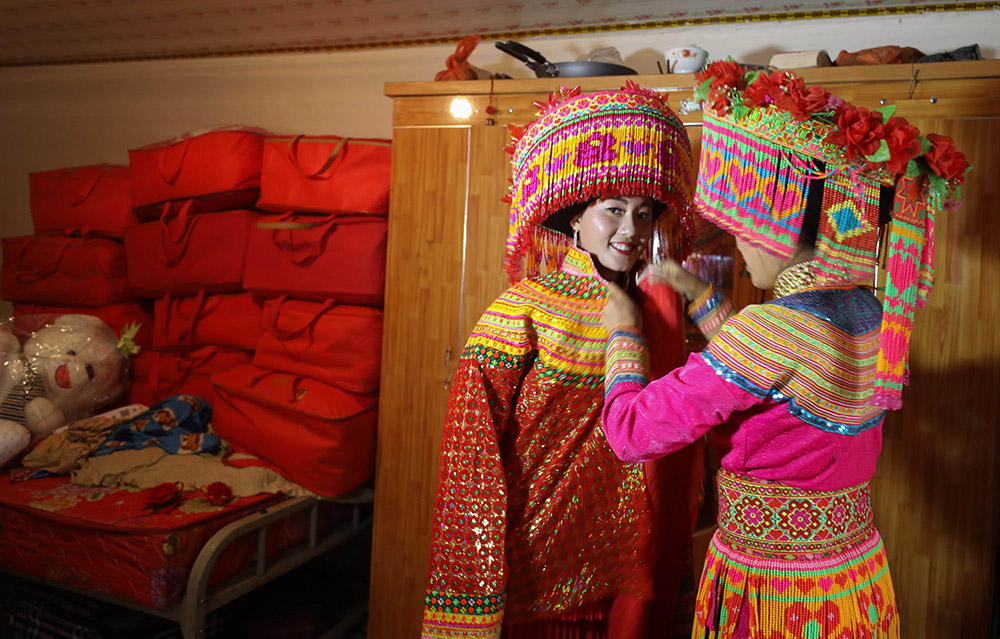 2月21日，在德昌县南山傈僳族乡小南山村，新娘张小芳（左）在穿传统嫁衣。