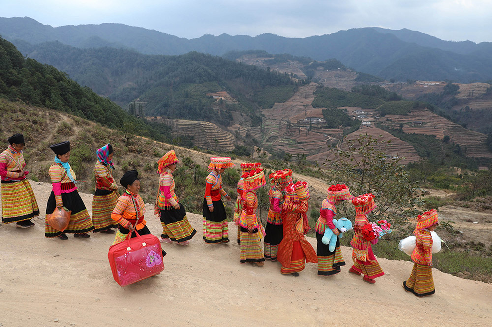 2月21日，在德昌县南山傈僳族乡小南山村，新娘张小芳（右四）和送亲队伍带着嫁妆向男方家走去。
