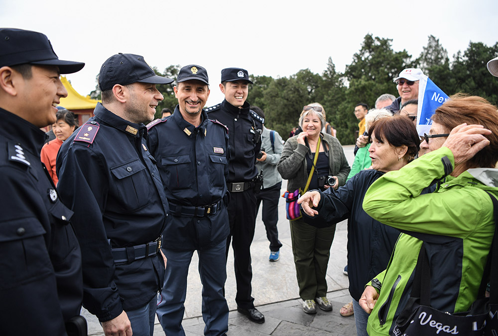 4月25日，在北京天坛进行中意警务联合巡逻的警员与来自加拿大的游客交流。