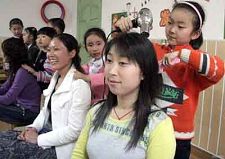 В городе Ляньюньган провинции Цзянсу дети в день матери пригласили своих мам в школу, они сами помогают мамам делать маску и прическу.