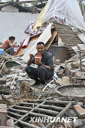 24 мая, местные жители, пострадавшие от землетрясения, в волости Лэйгу уезда Бэйчуань обедают перед рухнувшим домом.