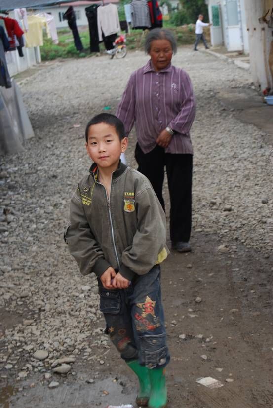 Мальчик и пожилая женщина идут через временное поселение для людей, оставшихся без крова после землетрясения 12 мая, возле Ханьвана провинции Сычуань.
