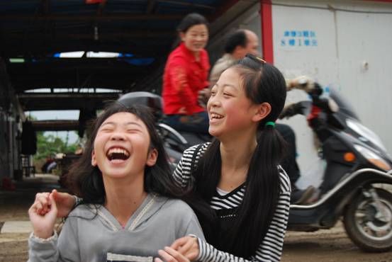Две девочки радостно фотографируются. Они живут возле Ханьвана провинции Сычуань, во временном поселении для людей, оставшихся без крова после землетрясения 12 мая.