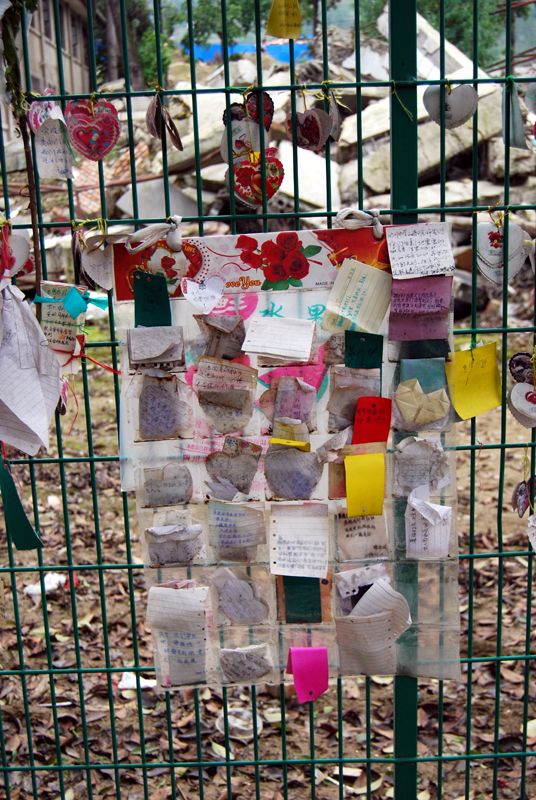 Цветы и трогательные послания учителям и школьникам, погибшим в средней школе Бэйчуань в землетрясении 2008 года