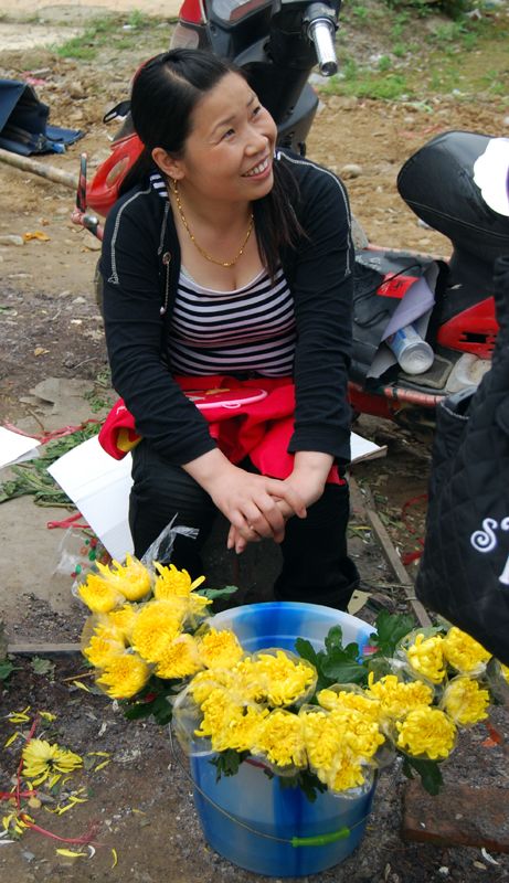 11 мая, женщина продает цветы людям, отдающим дань памяти погибшим в землетрясении 2008 года