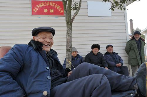 На фото: 73-летний пожилой мужчина разговаривает с другими пожилыми людьми во дворе благотворительного центра помощи города Шифан (27 января 2010 года).