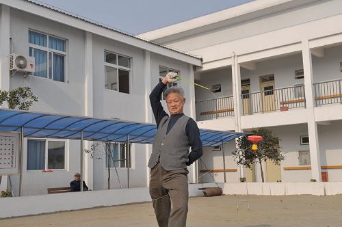 На фото: пожилой человек играет с бамбуковой катушкой во дворе центра помощи (27 января 2010 года).