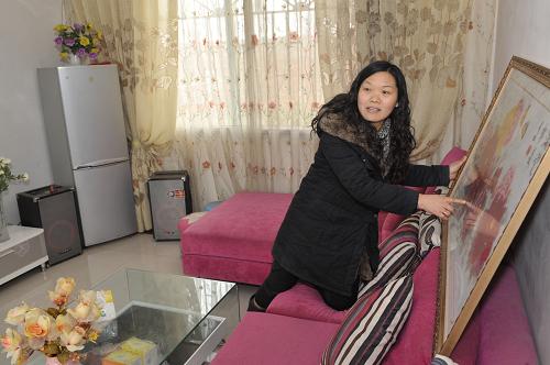На фото: Лю Тяньчжи демонстрирует изделие ручной работы в новом доме в деревне Дунюе города Шифан, построенном после землетрясения (26 января 2010 года).