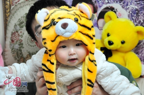 Милая китайская девочка в шапочке в виде головы тигра 1
