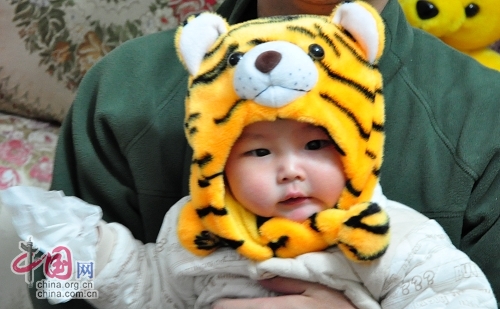 Милая китайская девочка в шапочке в виде головы тигра 3