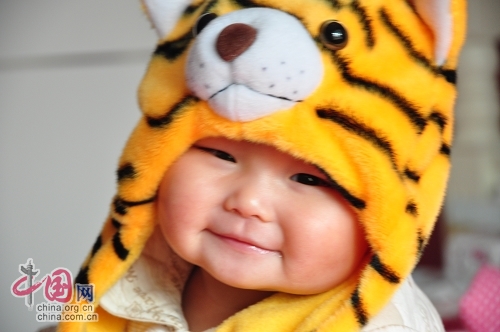 Милая китайская девочка в шапочке в виде головы тигра 4