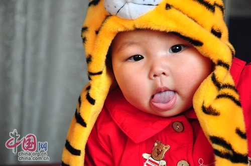 Милая китайская девочка в шапочке в виде головы тигра 7