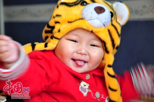 Милая китайская девочка в шапочке в виде головы тигра 8
