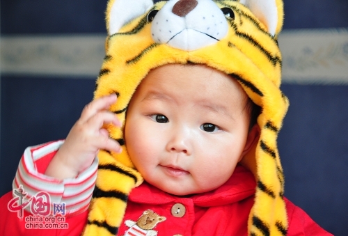 Милая китайская девочка в шапочке в виде головы тигра 9