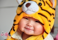 Милая китайская девочка в шапочке в виде головы тигра