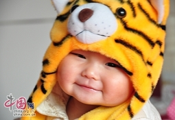 Милая китайская девочка в шапочке в виде головы тигра