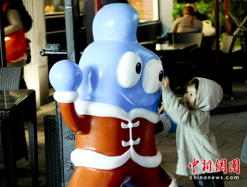 На фото: 26 апреля, иностранная девушка играет с талисманом Всемирной выставки в ресторане на улице Синьтяньди в Шанхае.