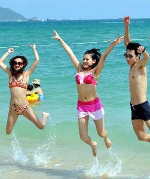 Туристы наслаждаются солнцем и морем в городе Санья во время празднования 1 мая